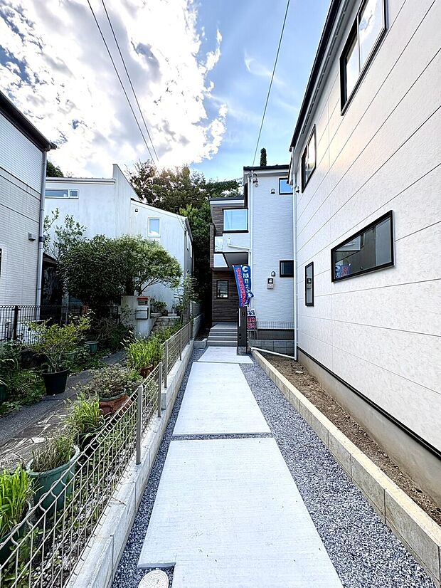 白い外壁が特徴の住宅と通路の外観写真です