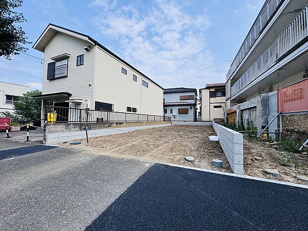 住宅地の空き地と周囲の住宅が見える現地写真です