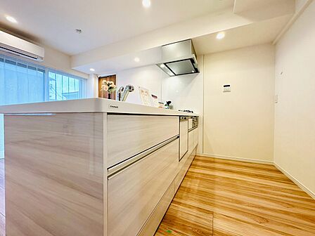 木目調の床とホワイトのキッチンが調和した室内です