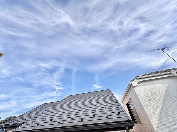 青空を背景にした住宅の屋根と外壁の様子