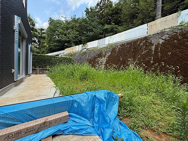 建物横の未整備な敷地と斜面の様子
