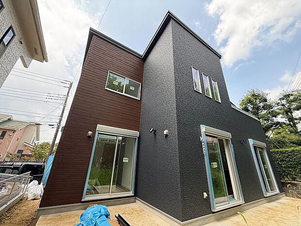 黒と茶のツートンカラーの二階建て住宅の外観です