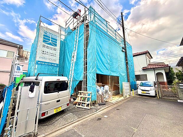 建築中の住宅外観、周囲に道路と駐車スペースあり