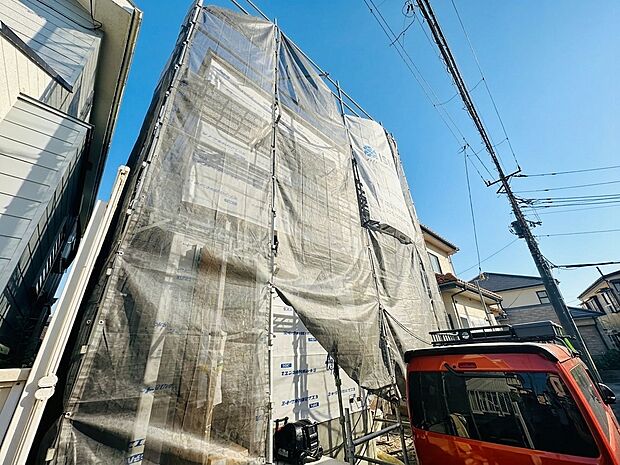 外装工事中の家と隣接する建物の様子です