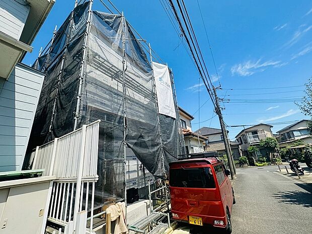 工事中の建物と周囲の街並みが見える外観写真です