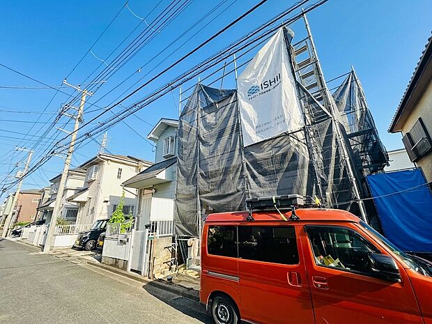 工事中の建物と赤い車が見える住宅街の外観