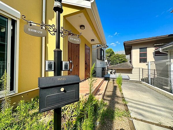 住宅の外観と郵便受けが見える通路の様子です