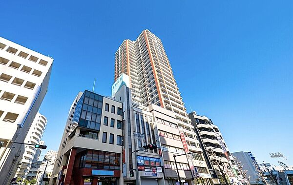 高層ビルと周囲の中低層建物が並ぶ街並みの外観写真です