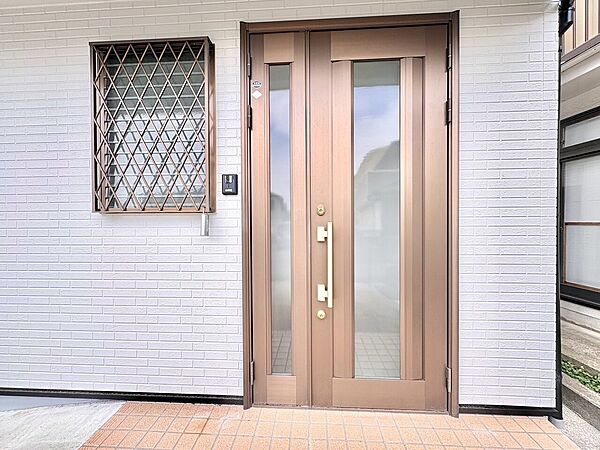格子窓と両開きの玄関ドアが見える住宅の玄関部分