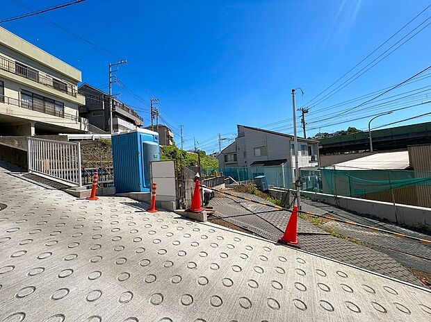 坂道沿いに建つ建物と青空の見える周辺環境