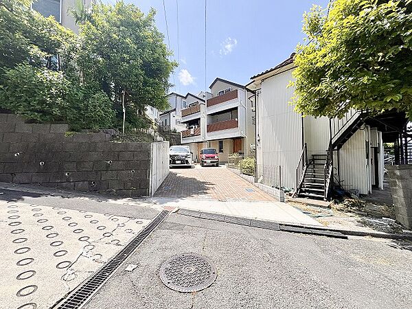 坂道の途中にある住宅の外観と周辺の緑豊かな環境