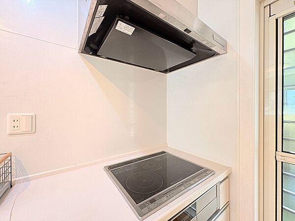 シンプルなIHクッキングヒーターと換気扇が設置されたキッチンの一部です