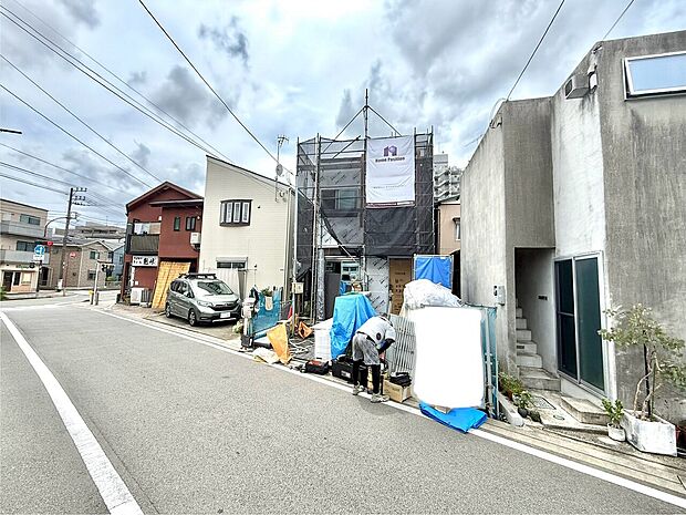 道路沿いに建つ住宅と作業中の人々の様子