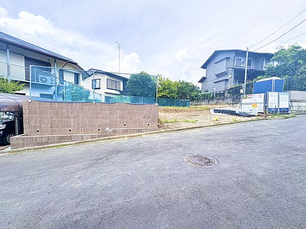 住宅地の高台にある敷地と舗装道路の様子