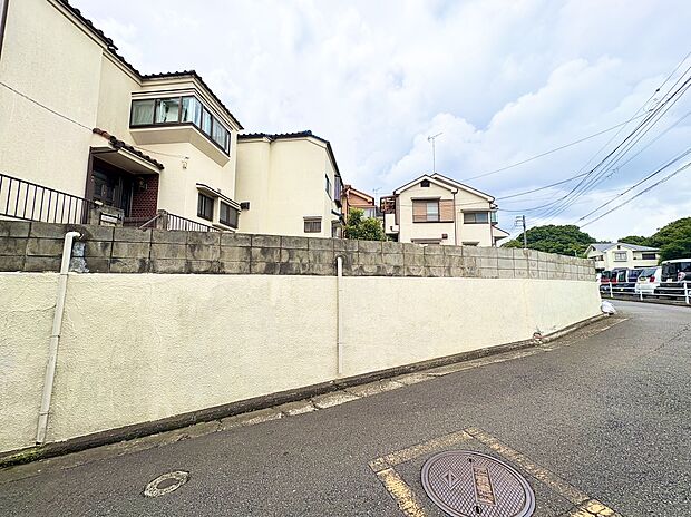 住宅街の道路沿いにある塀と住宅の外観