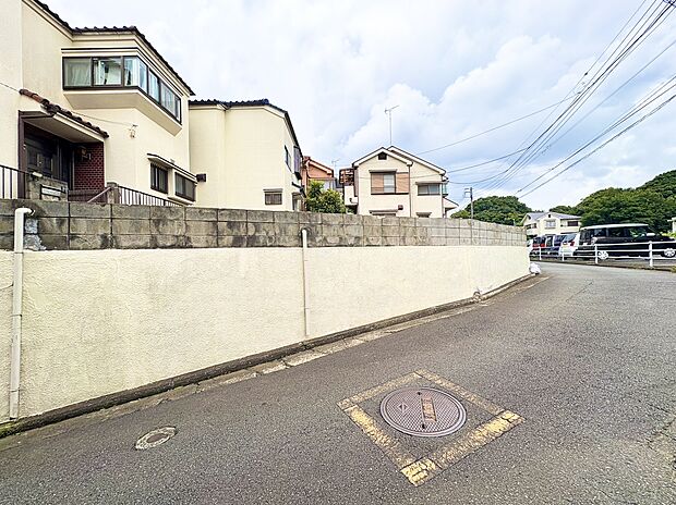 道路沿いの塀と住宅が見える静かな住宅街の風景