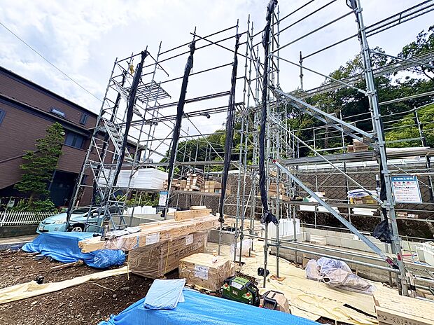 建築中の住宅の骨組みと資材が見える現場写真です