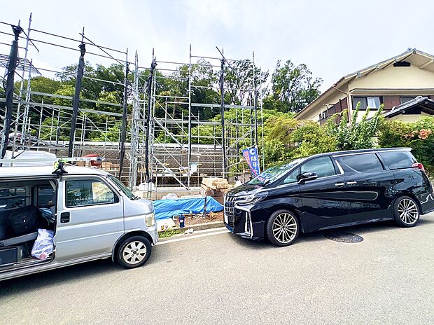 建築現場の前に並ぶ車と住宅の外観です