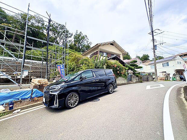 坂道沿いに建つ住宅と駐車中の車の様子