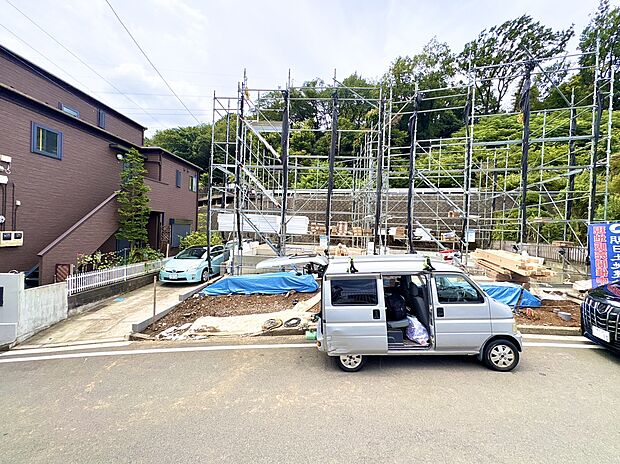 建築中の住宅と手前の軽トラック、周囲は緑豊かな環境です