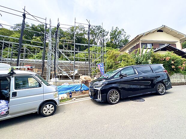 住宅街の道路沿いに駐車された車と周辺の住宅が見えます