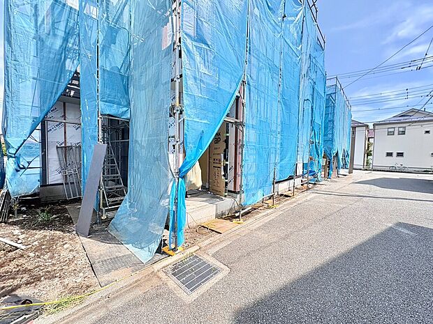建設中の住宅の外観、整備された道路沿いに位置する