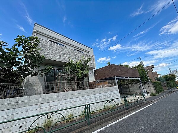白い塀と生け垣がある住宅の外観です