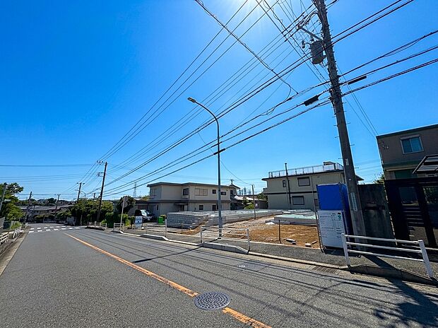 青空の下、広い道路沿いの住宅街の様子です