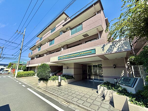 3階建てのマンションの外観、周囲に緑がある