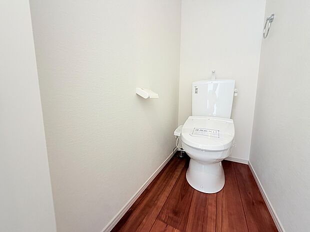 シンプルな白壁と木目の床のトイレ空間
