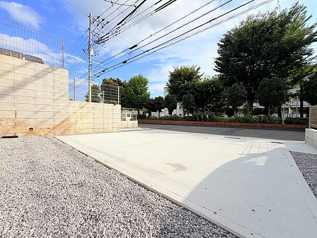 敷地内の広い駐車スペースと周囲の街路樹が見える風景