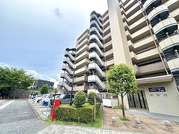 複数階建てのマンション外観と周辺の植栽が見える風景