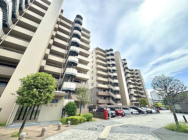 マンションの外観と駐車場の様子が見える風景