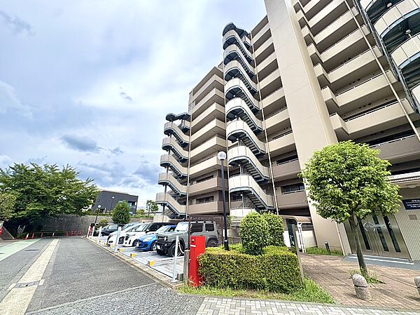 複数階のマンション外観と敷地内の駐車場が見える風景