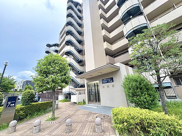 タイル貼りのマンションエントランスと周囲の植栽