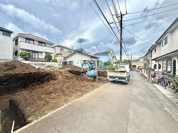 住宅街の更地と周辺の戸建て住宅が見える道路風景です