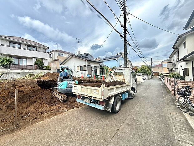 住宅地の道路沿いで工事用トラックが駐車している様子です