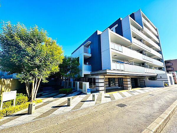 植栽と共に見えるモダンな5階建てマンションの外観