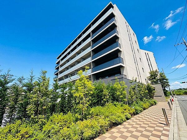 高層の集合住宅と緑豊かな植栽が見える外観写真です