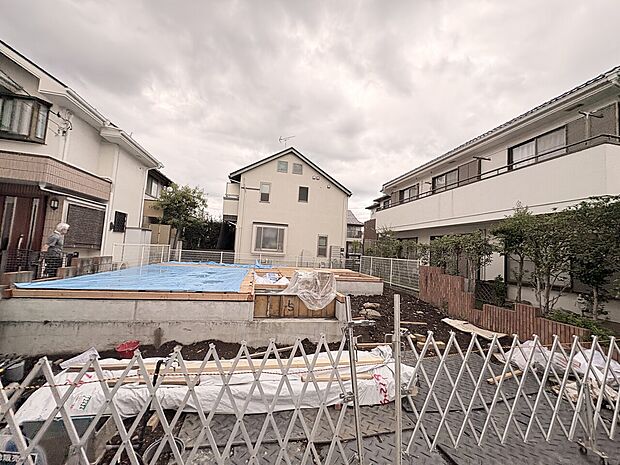 建物周辺の街並みとフェンス越しの敷地
