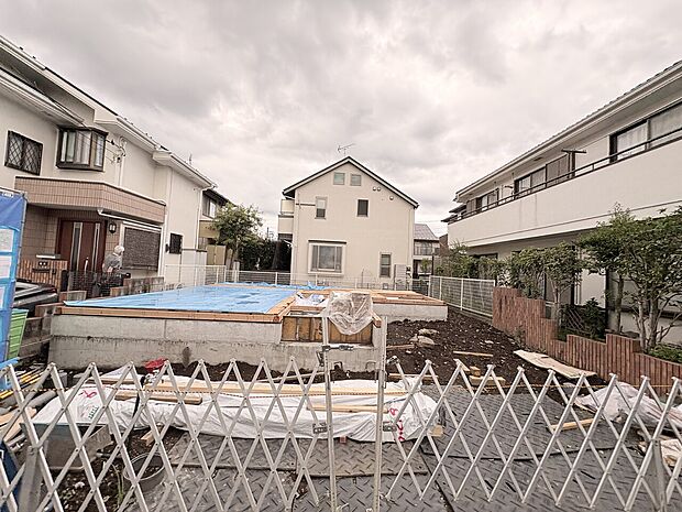 住宅街の建物とフェンス越しの空き地