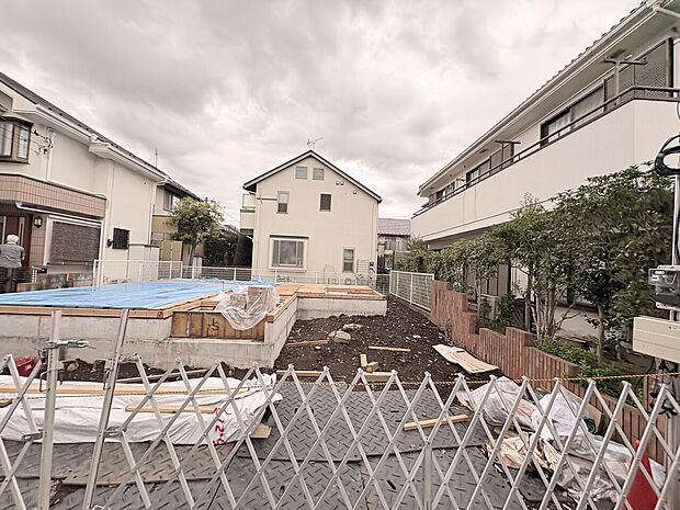 建物周辺の住宅街とフェンス越しの敷地