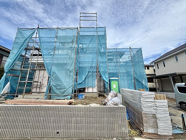 建築中の戸建て住宅外壁工事用の足場と養生シートがある