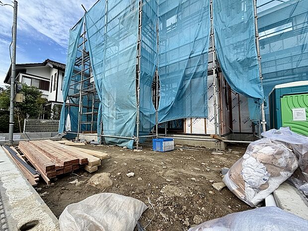 建築中の建物を覆う青い養生シートと資材