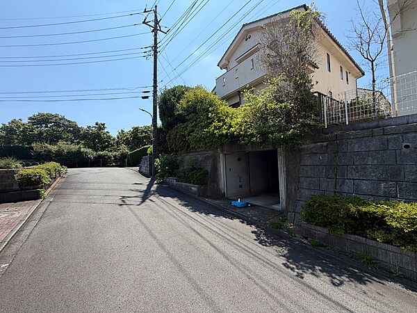 住宅が建ち並ぶ坂道の様子と周辺の緑が見えます