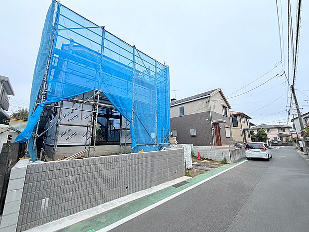 青い養生シートで覆われた建築中の建物と前面道路