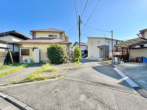 二階建て住宅の外観と周辺の街並みが見える風景です