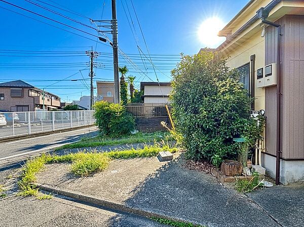 住宅の外観と庭、隣接道路が見える風景
