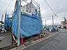 外観：建築中の建物を囲う青い防護シートと前面道路