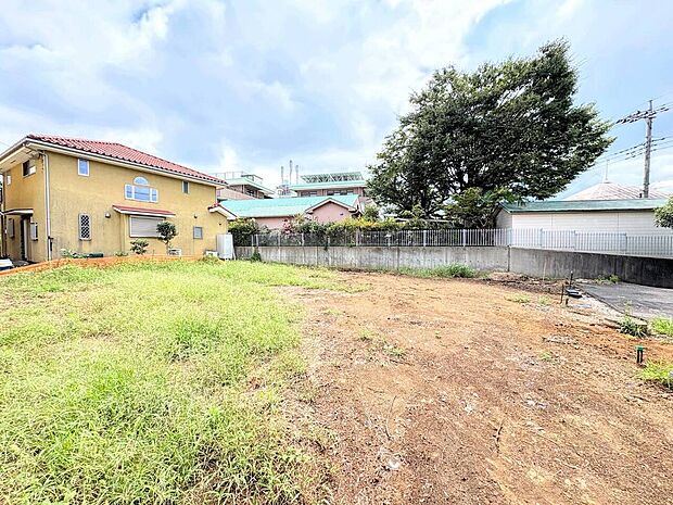 広めの更地と隣接する住宅が見える敷地の様子